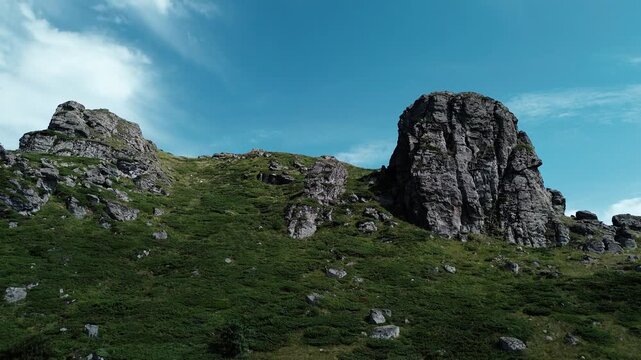 Rocky peaks of Babin Zub mountain in Stara Planina National Park, Serbia, rise above green forests under a blue sky. Aerial view from drone. Horizontal 4k footage