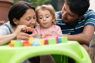 Parents engaging with their child in playful learning activities outdoors
