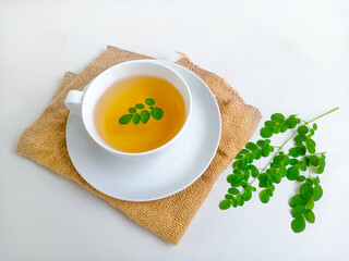 Moringa or Daun kelor herbal drink. A cup of Moringa tea. Boiled moringa leaves water in cup on white background. Healthy drink lifestyle