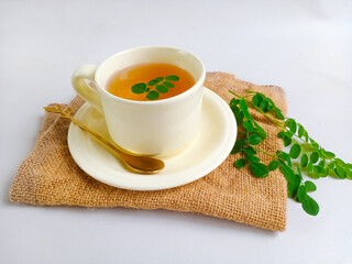 Moringa or Daun kelor herbal drink. A cup of Moringa tea. Boiled moringa leaves water in cup on white background. Healthy drink lifestyle