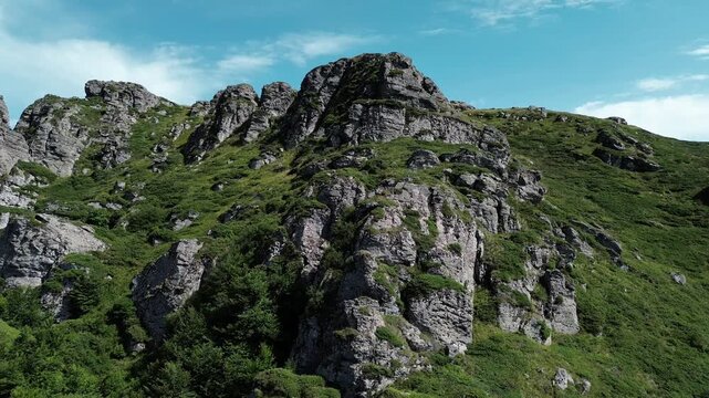 Rocky peaks of Babin Zub mountain in Stara Planina National Park, Serbia, rise above green forests under a blue sky. Aerial view from drone. Horizontal 4k footage