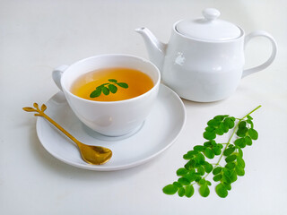 Moringa or Daun kelor herbal drink. A cup of Moringa tea. Boiled moringa leaves water in cup on white background. Healthy drink lifestyle