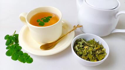 Moringa or Daun kelor herbal drink. A cup of Moringa tea. Boiled moringa leaves water in cup on white background. Healthy drink lifestyle