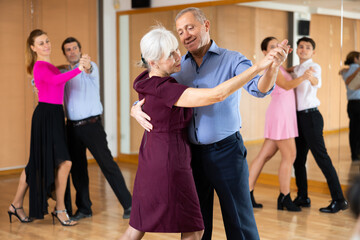 Naklejka premium among small group of students at dance lesson, older positive partners dance waltz