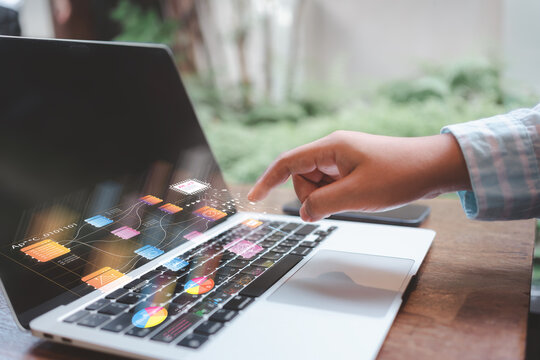 Hand interacting with a laptop’s holographic data pipeline and AI workflow, showing dashboards, flowcharts, and analytics for digital decision-making