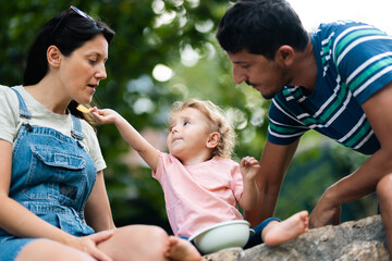 Young family enjoying time outdoors with their child sharing food