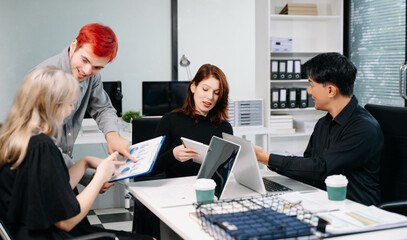 Diverse business team collaborating in a meeting with laptops, tablets, and reports, symbolizing planning, analysis, teamwork, and professional success.