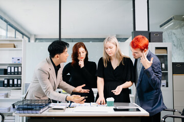 Happy businesspeople while collaborating on a new project in an office. Group of diverse businesspeople using a laptop and tablet in office.