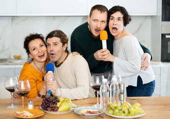 Party and karaoke at the house for fun social event or gathering together in celebration. Happy people celebrating friendship, birthday or festive season singing at home