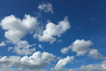 Fluffy white clouds against deep blue summer sky
