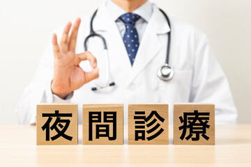 「夜間診療」と書かれたブロックとOKサインをする医師