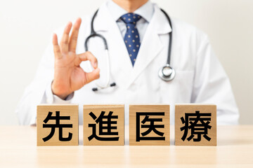 「先進医療」と書かれたブロックとOKサインをする医師