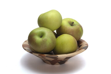 Green apples in a wooden bowl.   The apples are on a white background.  The look is simplistic. The subject is centrally framed.