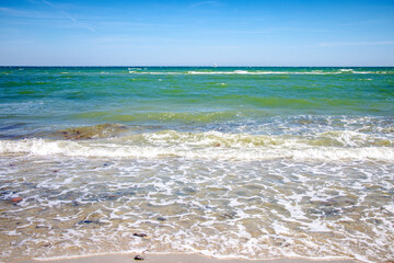 Waves gently rolling on sandy beach on sunny day