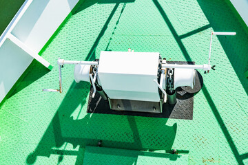 Winch with anchor chain on green ship deck