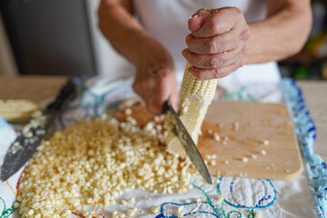 Woman's hands cutting corn kernels from cob