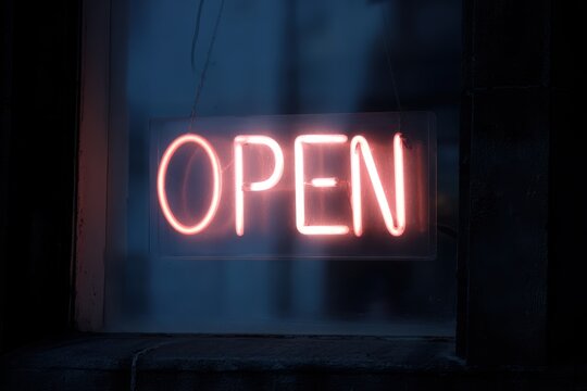 A neon "OPEN" sign, with "SALE" added, glowing in a window