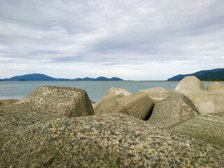 テトラポットとも呼ばれる消波ブロックが設置されている海沿いの防波堤のイメージ