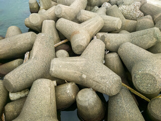 テトラポットとも呼ばれる消波ブロックが設置されている海沿いの防波堤のイメージ