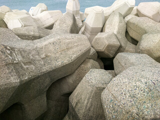 テトラポットとも呼ばれる消波ブロックが設置されている海沿いの防波堤のイメージ