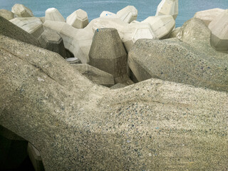 テトラポットとも呼ばれる消波ブロックが設置されている海沿いの防波堤のイメージ