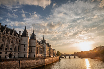 La Conciergerie along the Seine with Pont Neuf at dusk in Paris. The medieval palace and former...