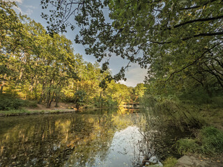 Wide view of Lake Tresnja near Avala in Belgrade, Serbia. Calm water reflects leafy trees under warm afternoon light. Jezero Tresnja is a small lake of Serbia.