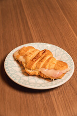 Close-up view of a croissant on a wooden table.