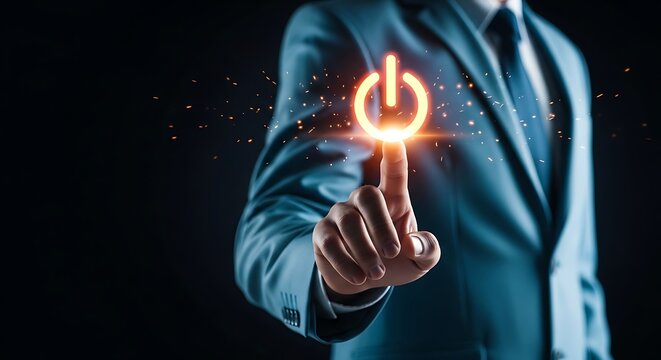 Businessman in a suit touching a glowing power button symbol with his finger, representing startup, technology, and innovation