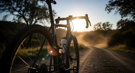 Obraz premium Gravel Bike Adventure on a Dusty Country Road at Sunrise.