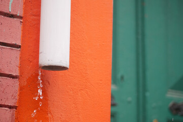 Rainwater flowing through a downspout on a colorful wall