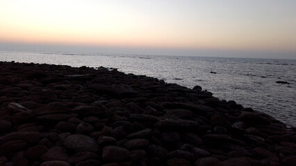 Dark rocky shoreline meets calm ocean at twilight water coast
