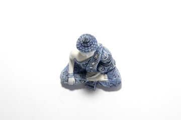 Serene white and blue decorative Buddha statue in a meditative pose, isolated on a white...