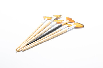 A unique black-handled fan paintbrush stands out among a group of similar light-handled brushes. A conceptual symbol of diversity, inclusion, and breaking the mold in art and professional fields.