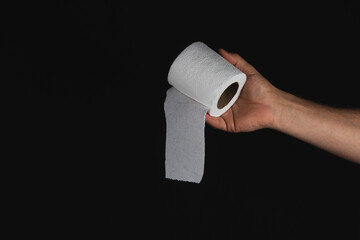 Hand holding roll of grey paper towel against black background
