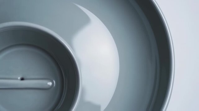 Close-up of a grey, circular dish with a recessed inner bowl and a spout