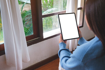Mockup image of a woman holding tablet with blank desktop white screen at home