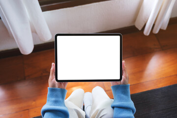 Top view mockup image of a woman holding tablet with blank desktop white screen at home