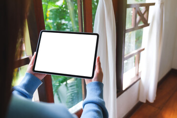 Mockup image of a woman holding tablet with blank desktop white screen at home