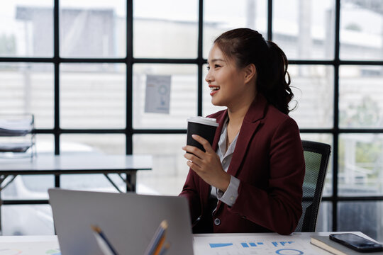 Asian business Smiling woman in formal suit in the office happy and cheerful during using slaptop and working.
