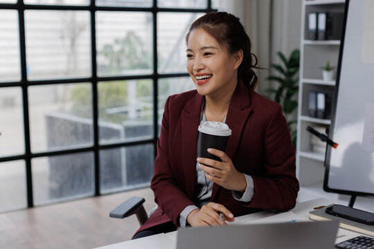 Asian business Smiling woman in formal suit in the office happy and cheerful during using slaptop and working.
