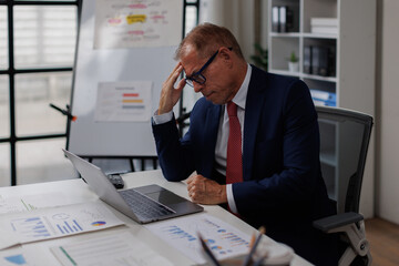 Frustrated businessman with laptop in hands. Worried trader man failed on stock exchange failed in...