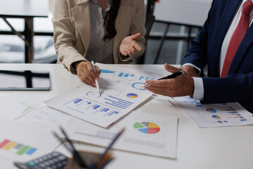 Two colleagues are sitting at the meeting room and discussing charts financial report and statistics.
