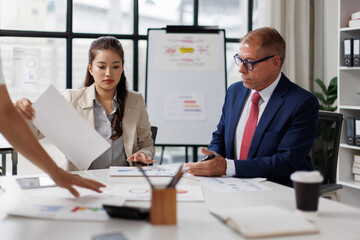 Two colleagues are sitting at the meeting room and discussing charts financial report and statistics.
