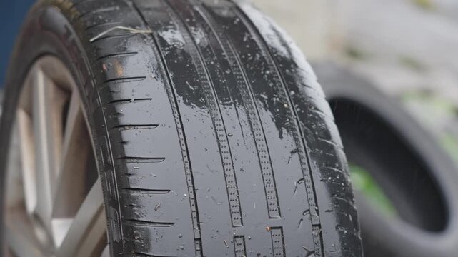 Closeup of wet worn tire as hand checks tread depth and confirms dangerous low condition