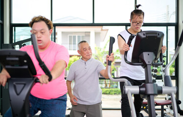 Obraz premium A man with down syndrome exercising on an elliptical machine under the guidance of an elderly man at the gym