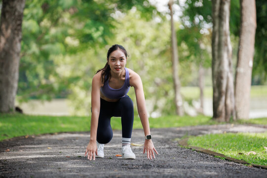 Young woman in sportswear getting ready to run as an athlete in a park, preparing for exercise and training