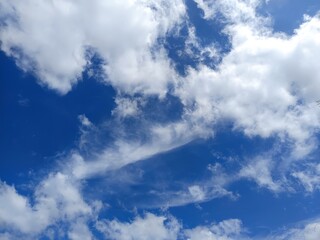 Sky's Serenity: A panoramic view of a radiant blue sky adorned with fluffy, white clouds. The scene embodies a sense of tranquility and limitless potential.