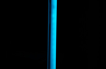 A single, minimalist vertical blue neon light streak or tube on a solid black background, a technology concept.