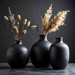 Three black vases with dried grasses against a dark backdrop